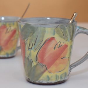 handgetöpferte Keramiktasse mit handgemachten Unterteller aus Keramik in weiß und Vorratsdose aus Keramik im Hintergrund