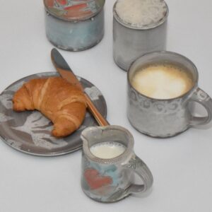 Handgetöpferter Unterteller aus Keramik in blau mit einem Croissant und einer Gabel auf dem Teller.